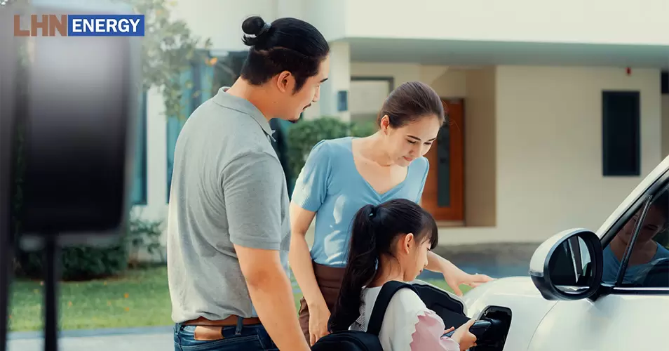 Family recharging an electric vehicle at charging station